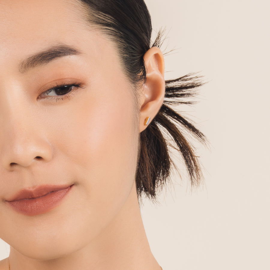 Fine and dainty studs. Model is wearing solid yellow gold earrings set with opals