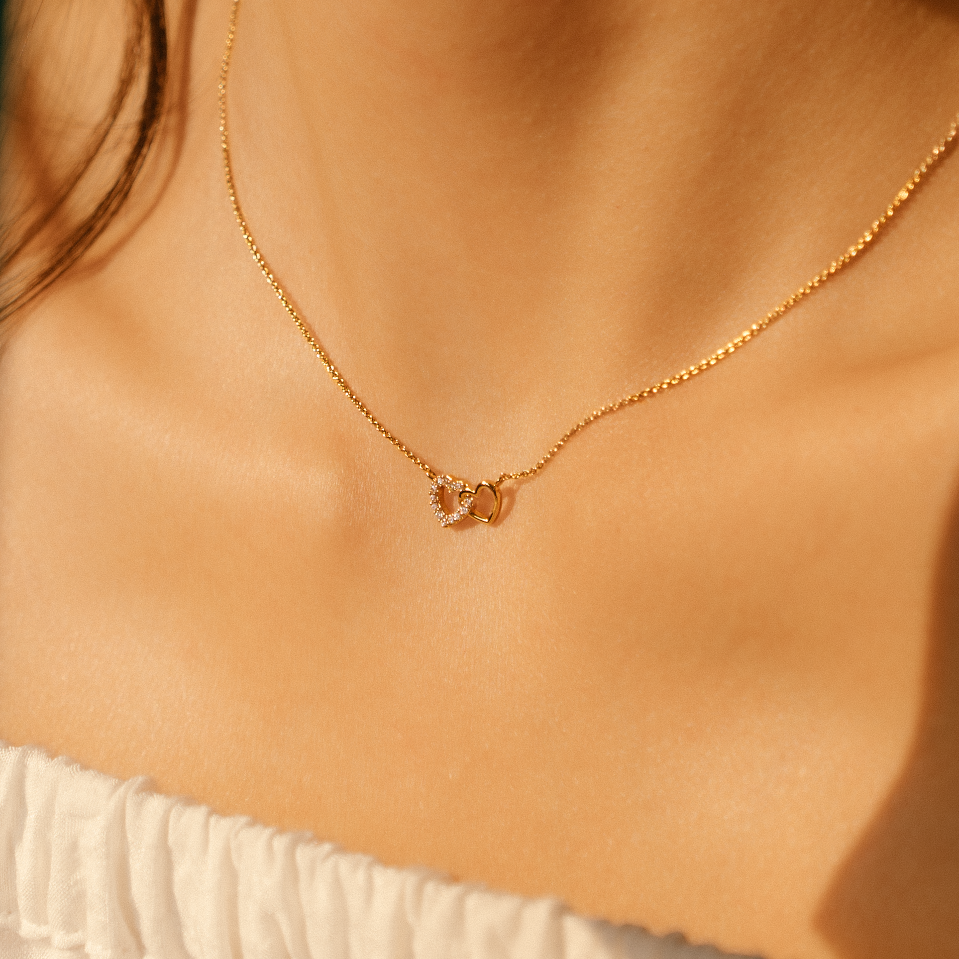 Model is wearing elegant and dainty necklace with cubic zirconia stones in gold.
