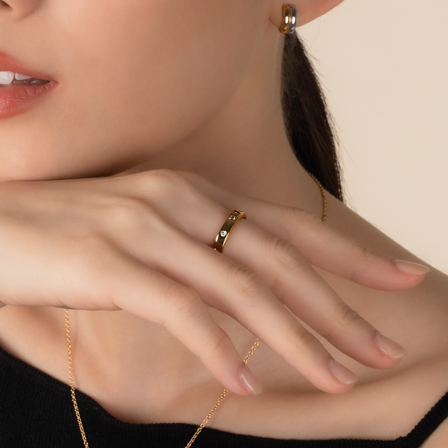 Model is wearing elegant and minimalist ring in gold, set with cubic zirconia stones.