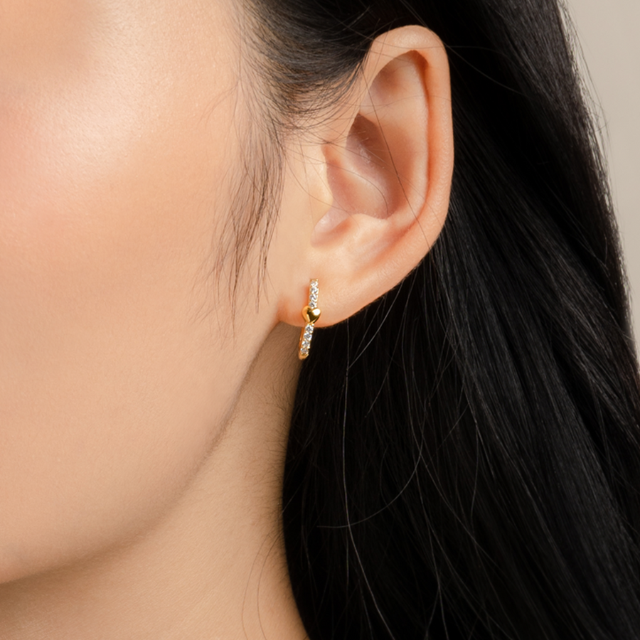 Model wears charming and dainty huggies in gold with cubic zirconia.