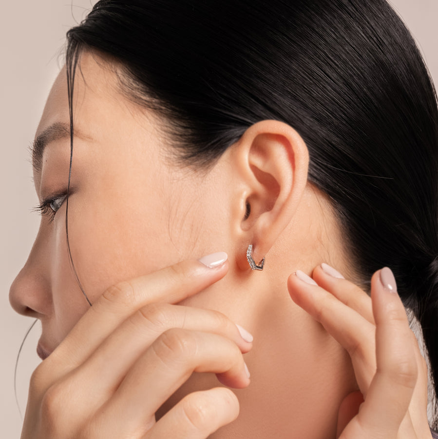 Elegant and statement earrings. Model wears silver hexagonal huggies set with cubic zirconia stones.