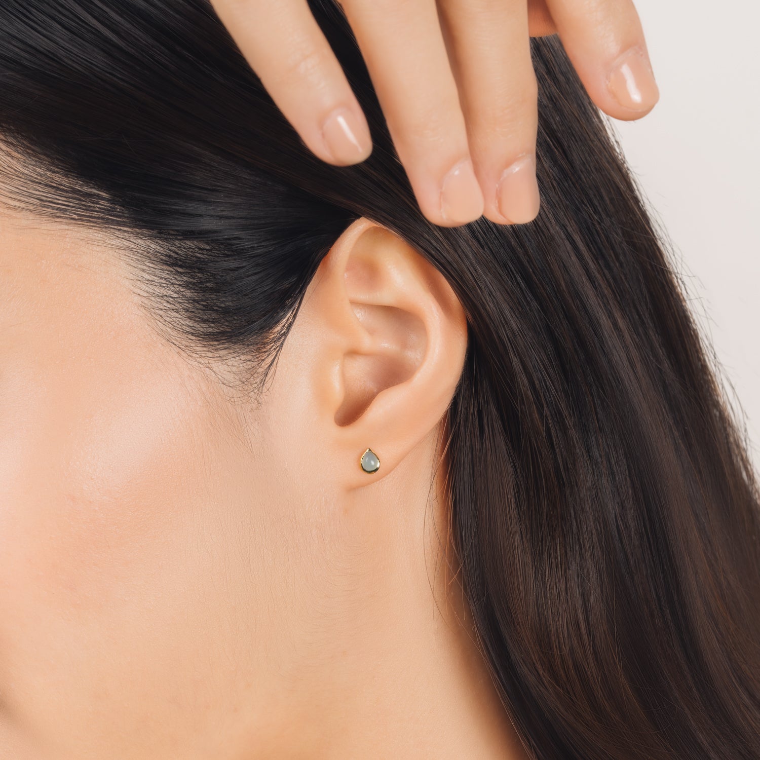 Fine and dainty studs. Model is wearing solid yellow gold earrings set with chalcedony gemstones