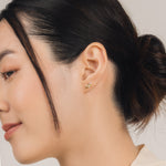 Fine and dainty studs. Model is wearing solid yellow gold earrings set with opals and conflict free diamonds