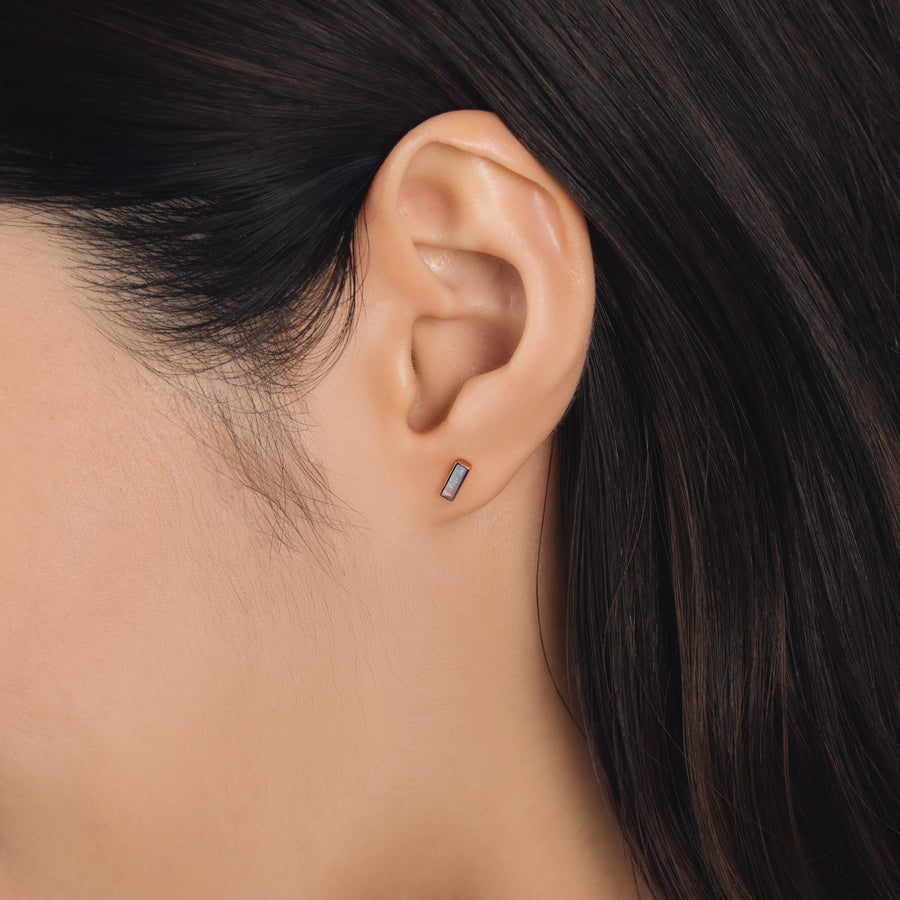 Fine and dainty studs. Model is wearing solid rose gold earrings set with opal gemstones