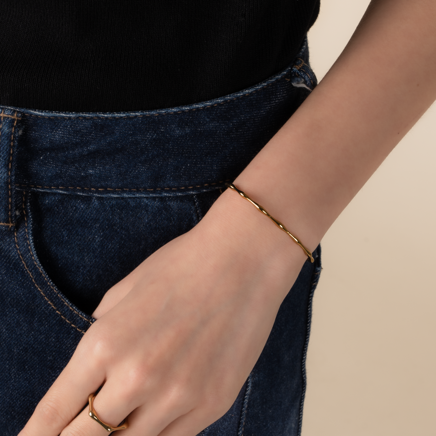 Model is wearing minimalist and sleek bangle in gold.