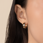 Model is wearing elegant and minimalist huggies with mixed metal in 925 silver and gold in medium.