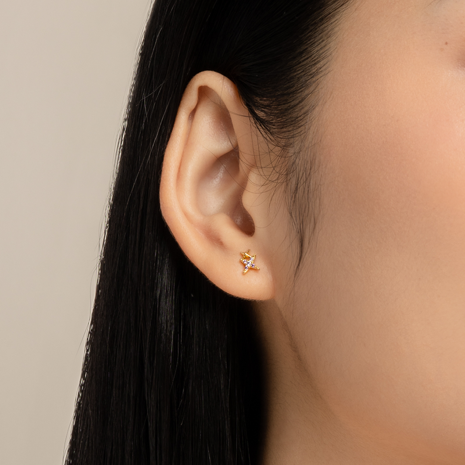 Simple and dainty earrings. Model wears gold studs set with cubic zirconia stones.
