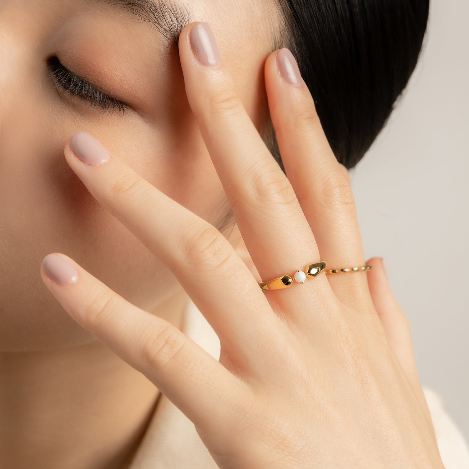 Model wears elegant and minimalist gold ring set with opals.